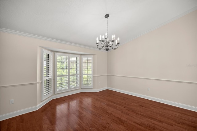 spare room featuring crown molding, wood-type flooring, and an inviting chandelier