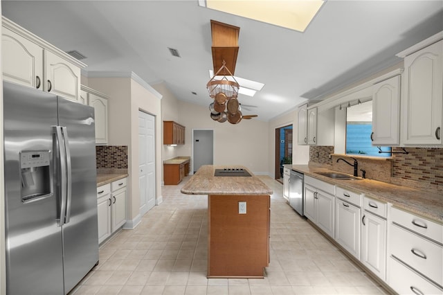 kitchen with a skylight, sink, a center island, tasteful backsplash, and appliances with stainless steel finishes