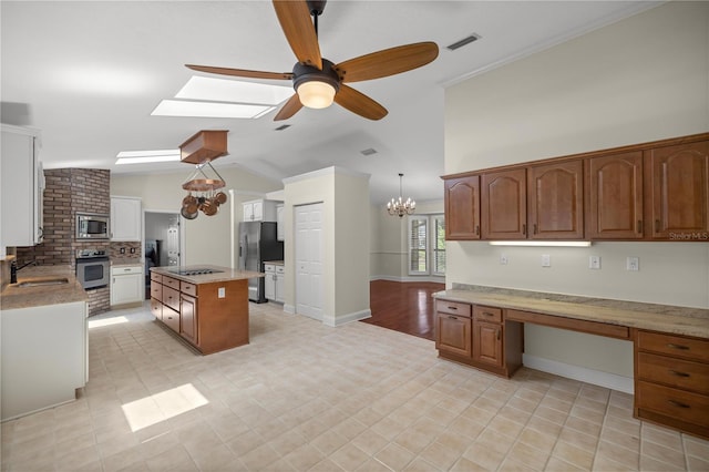 kitchen featuring stainless steel appliances, lofted ceiling with skylight, decorative light fixtures, a kitchen island, and ceiling fan with notable chandelier