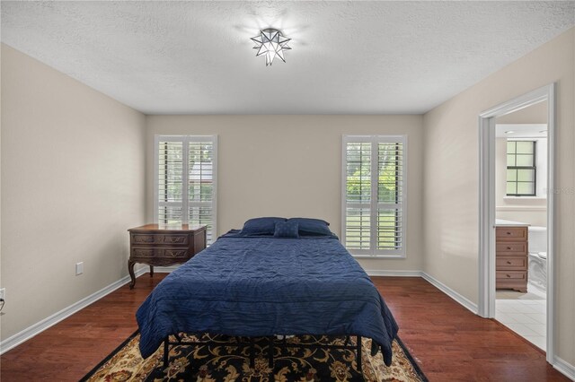 bedroom featuring connected bathroom, multiple windows, and hardwood / wood-style flooring