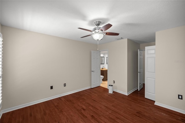 unfurnished bedroom featuring connected bathroom, ceiling fan, and dark wood-type flooring