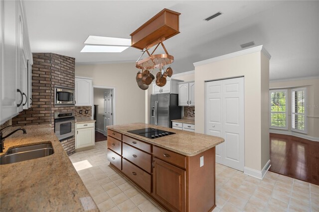 kitchen with stainless steel appliances, lofted ceiling with skylight, sink, white cabinetry, and backsplash