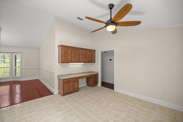 kitchen featuring ceiling fan, built in desk, vaulted ceiling, and ornamental molding