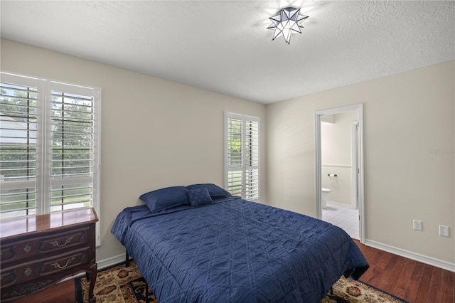 bedroom featuring a textured ceiling, multiple windows, ensuite bath, and hardwood / wood-style flooring