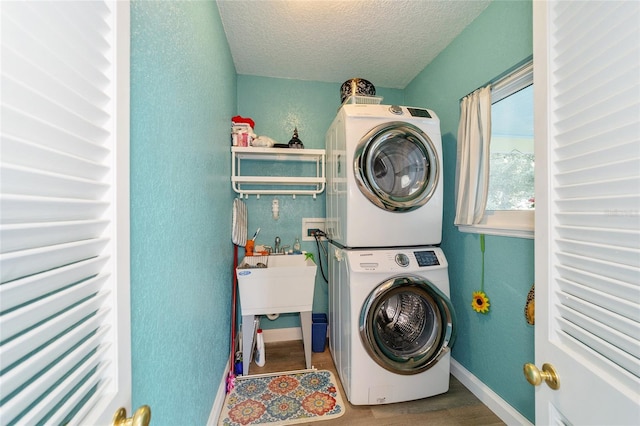 laundry room featuring a textured ceiling, wood-type flooring, and stacked washer and dryer