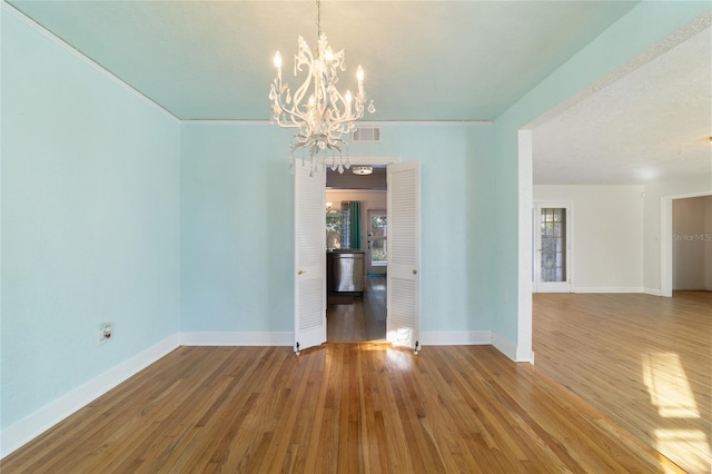 empty room with hardwood / wood-style floors and an inviting chandelier