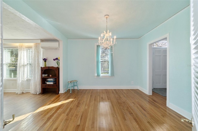 unfurnished dining area with an AC wall unit, light hardwood / wood-style flooring, and an inviting chandelier