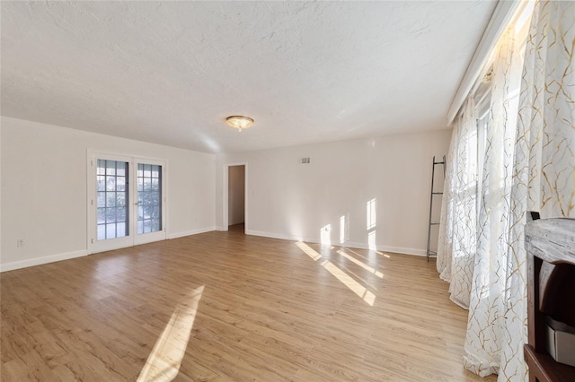 unfurnished living room featuring light hardwood / wood-style flooring and a textured ceiling