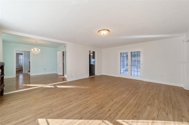 empty room featuring light hardwood / wood-style floors and a notable chandelier