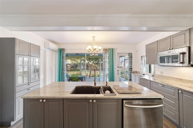 kitchen with a wall mounted air conditioner, a center island with sink, sink, a notable chandelier, and stainless steel appliances