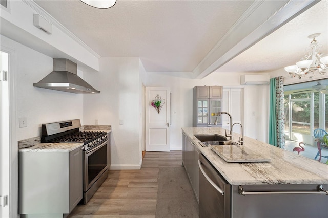 kitchen with gray cabinetry, sink, wall chimney exhaust hood, a wall mounted AC, and appliances with stainless steel finishes