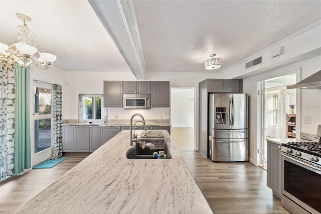 kitchen featuring beamed ceiling, appliances with stainless steel finishes, decorative light fixtures, and gray cabinetry