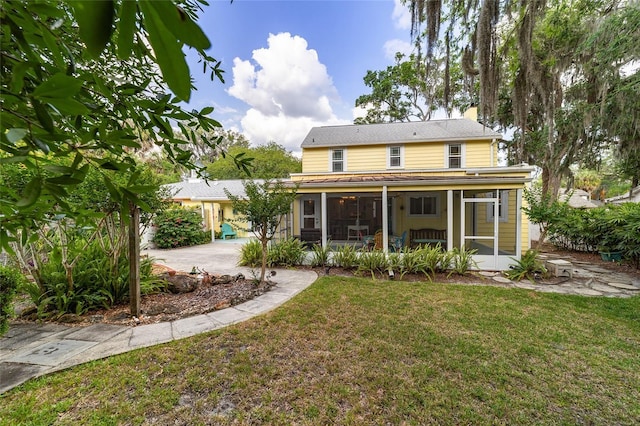 rear view of property featuring a lawn and a sunroom