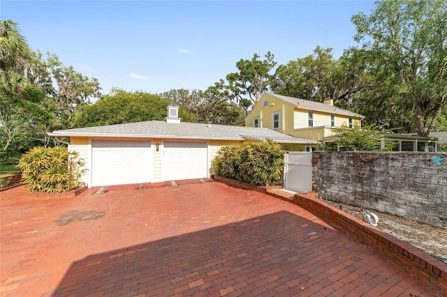 exterior space featuring a garage, decorative driveway, and fence