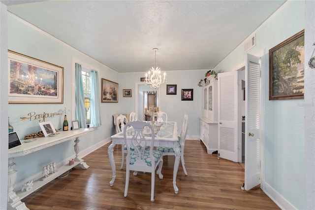 dining area featuring a chandelier, visible vents, baseboards, and wood finished floors