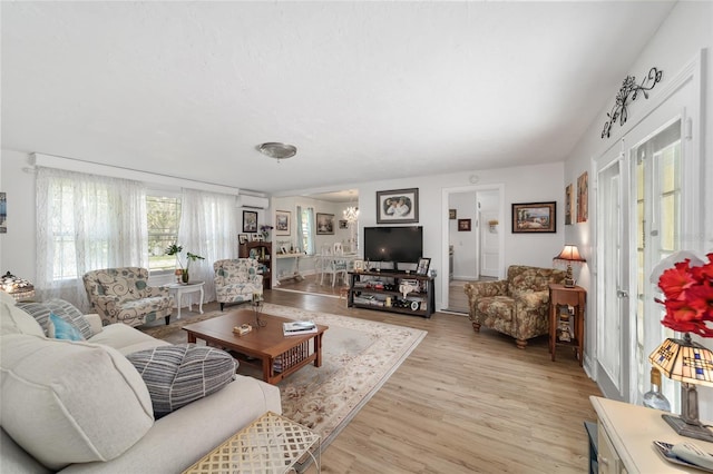 living room featuring light wood finished floors and an AC wall unit