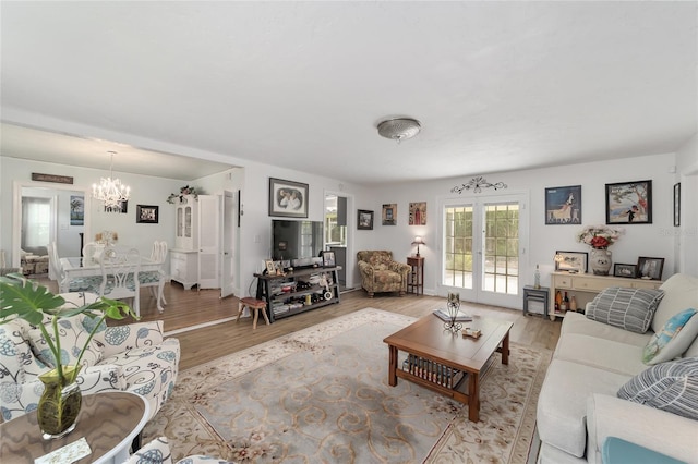 living area with light wood-type flooring, a chandelier, and french doors