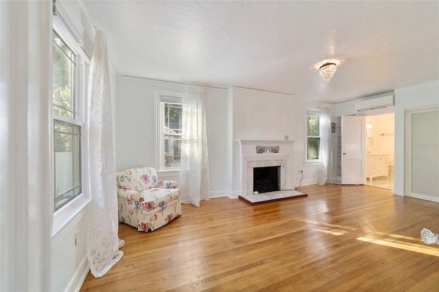 unfurnished living room featuring light wood-style flooring, a high end fireplace, baseboards, and a wall mounted air conditioner