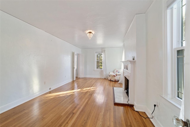 unfurnished living room with a fireplace, light wood-style flooring, and baseboards