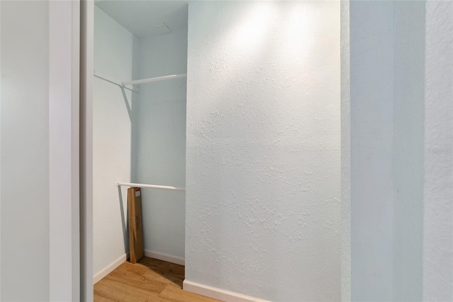 bathroom featuring a textured wall, baseboards, and wood finished floors