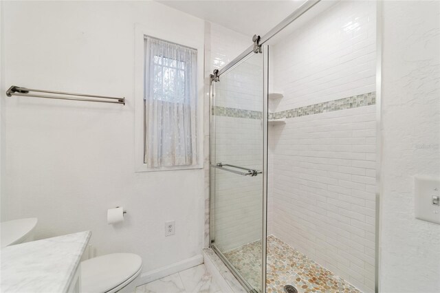 full bathroom with marble finish floor, a shower stall, toilet, and baseboards