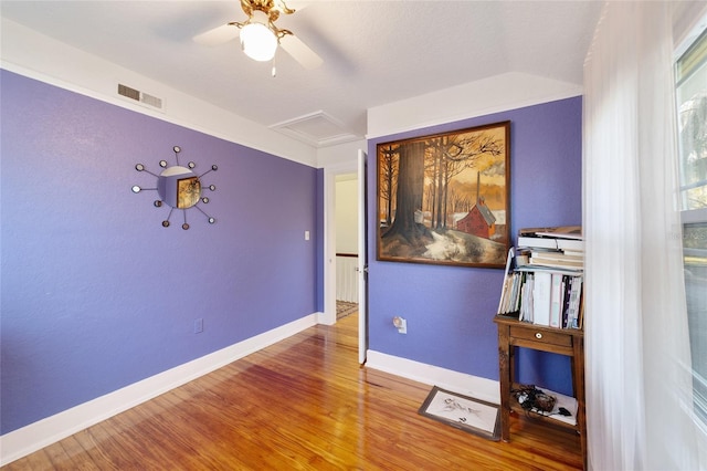 unfurnished bedroom with visible vents, attic access, a ceiling fan, wood finished floors, and baseboards