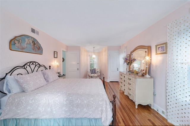 bedroom with baseboards, visible vents, and light wood finished floors