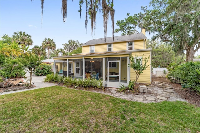 rear view of house featuring a sunroom, a chimney, fence, and a yard