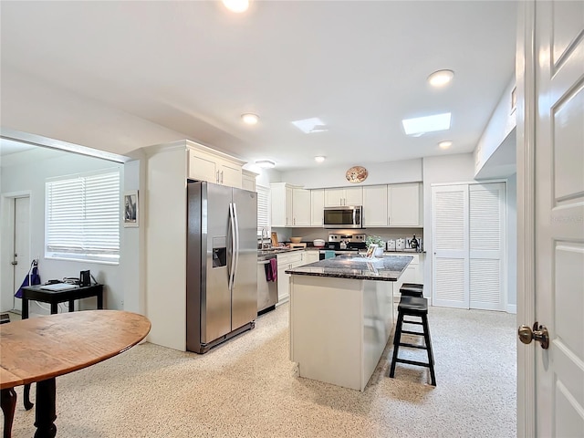 kitchen featuring a center island, a kitchen breakfast bar, white cabinetry, and appliances with stainless steel finishes