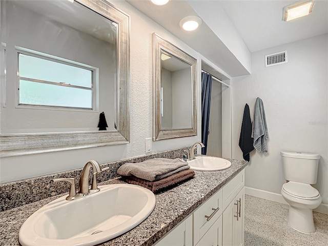 bathroom featuring dual sinks, vanity with extensive cabinet space, and toilet