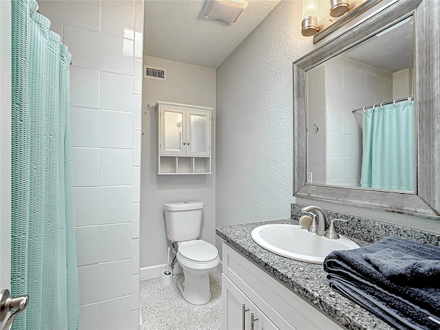 bathroom featuring a textured ceiling, vanity, and toilet