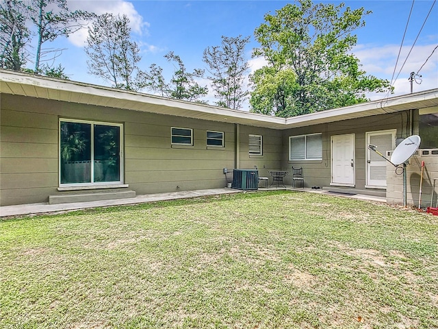 rear view of property with central AC and a lawn