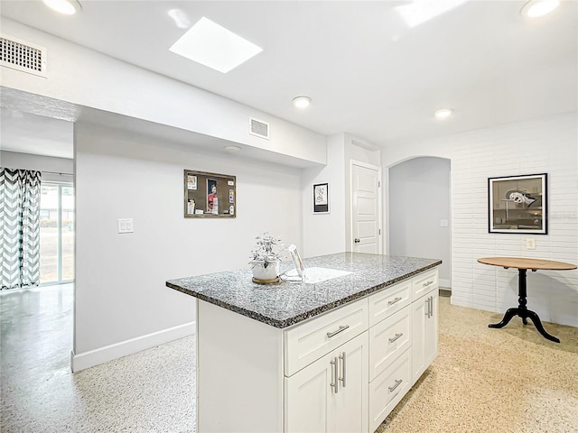 kitchen with dark stone counters, a center island, and white cabinetry