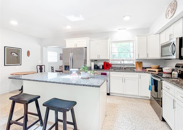 kitchen featuring a kitchen island, stainless steel appliances, white cabinets, a breakfast bar area, and sink