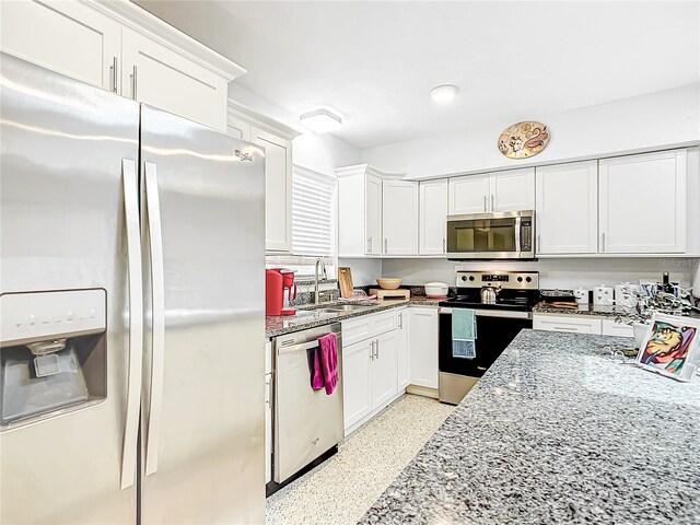 kitchen featuring appliances with stainless steel finishes, sink, white cabinets, and light stone countertops