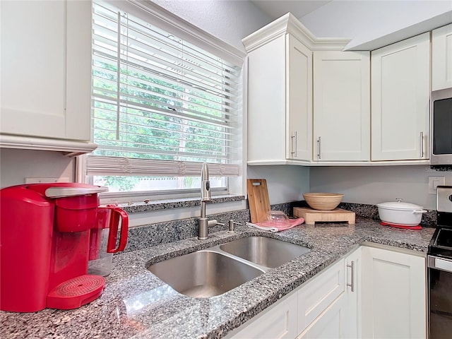 kitchen with light stone countertops, stainless steel appliances, white cabinets, and sink