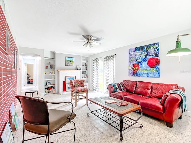 living room with brick wall, built in shelves, and ceiling fan