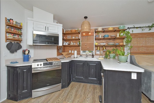 kitchen with light hardwood / wood-style flooring, tasteful backsplash, white cabinetry, appliances with stainless steel finishes, and sink