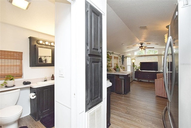 bathroom with ceiling fan, toilet, wood-type flooring, vanity, and lofted ceiling