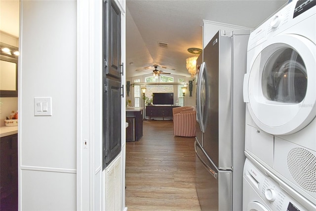 clothes washing area with stacked washer and dryer, ceiling fan, and hardwood / wood-style flooring