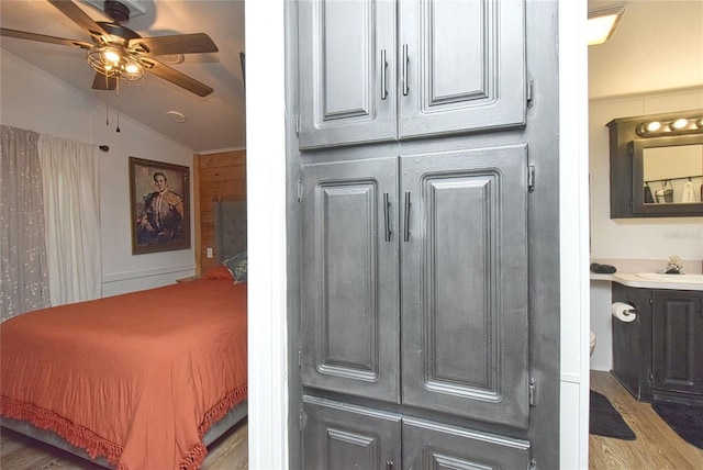 bedroom featuring light hardwood / wood-style floors, sink, ceiling fan, and vaulted ceiling