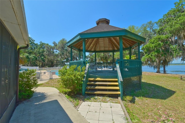 view of property's community featuring a deck with water view, a gazebo, and a lawn