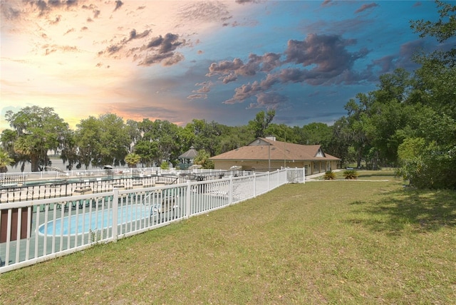 yard at dusk featuring a fenced in pool