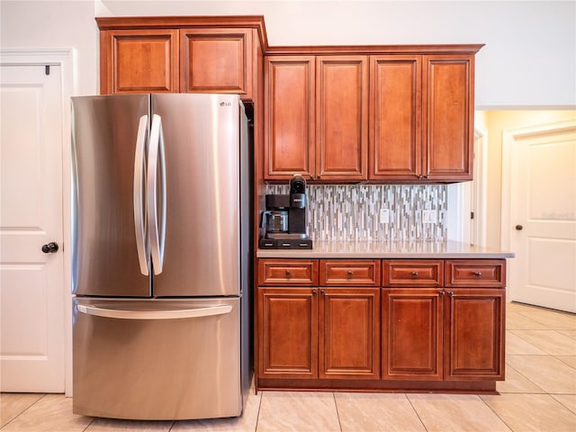 kitchen with backsplash, stainless steel refrigerator, and light tile floors