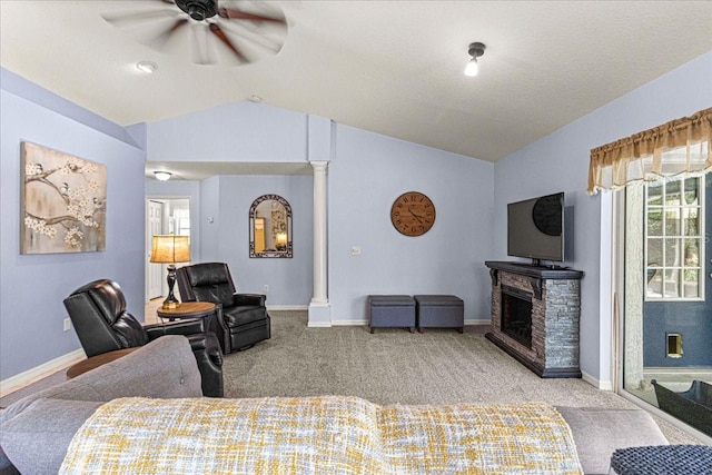 living room with lofted ceiling, a stone fireplace, ceiling fan, ornate columns, and light colored carpet