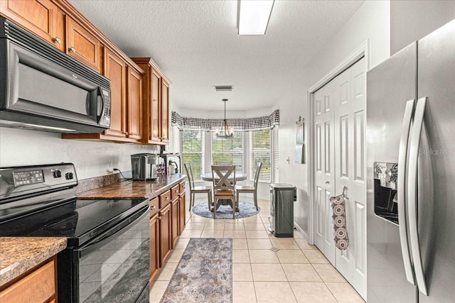 kitchen with an inviting chandelier, black appliances, hanging light fixtures, light tile patterned floors, and a textured ceiling