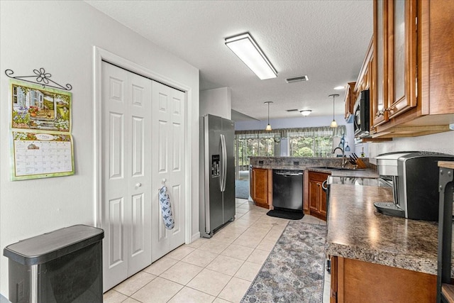 kitchen featuring sink, stainless steel appliances, pendant lighting, a textured ceiling, and light tile patterned floors