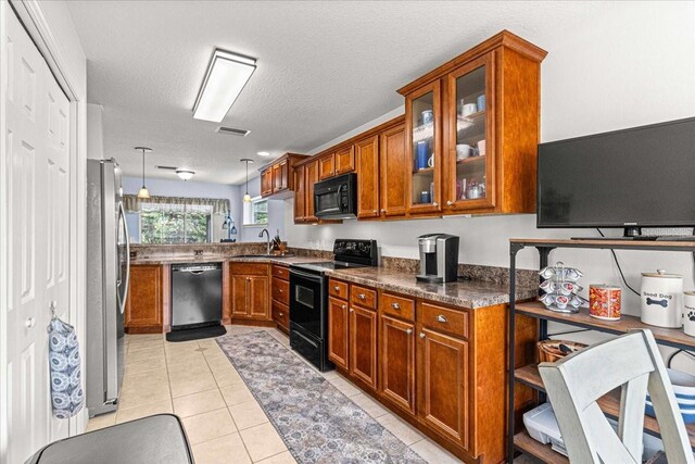 kitchen with dark stone counters, a textured ceiling, black appliances, light tile patterned floors, and hanging light fixtures