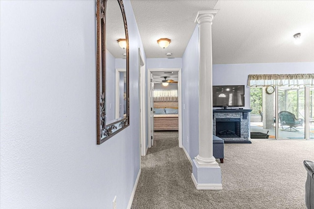 hallway with carpet flooring, a textured ceiling, and decorative columns