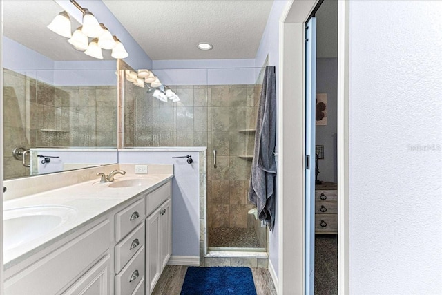 bathroom with a textured ceiling, vanity, wood-type flooring, and a shower with door